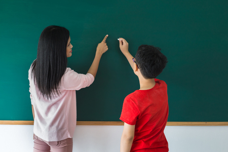 Little boy standing in the classroom while learning  with his teacherの写真素材
