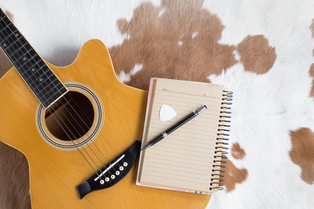 Classic acoustic guitar and and note with pen  for composing on leather backgroundの写真素材