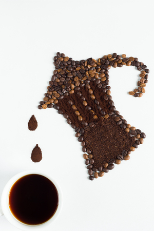 Coffee beverage concept , Moka pot shape made from coffee bean with coffee ground ,fill coffe to cup on white backgroundの写真素材