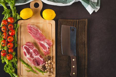 Pieces of raw pork steak with knife and ingredient, flat lay image with copy space for your textの写真素材