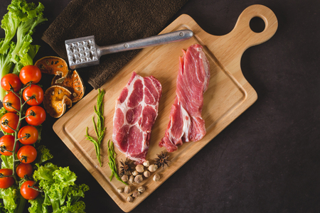 Pieces of raw pork steak with spices and herbs rosemary with meat  hammer, flat lay image with copy space for your textの写真素材