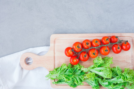 Cherry tomatoes  on cutting board over concreat table background , flat lay image with copy space for your textの写真素材