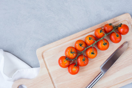 Cherry tomatoes with knife on cutting board over concreat table background , flat lay image with copy space for your textの写真素材