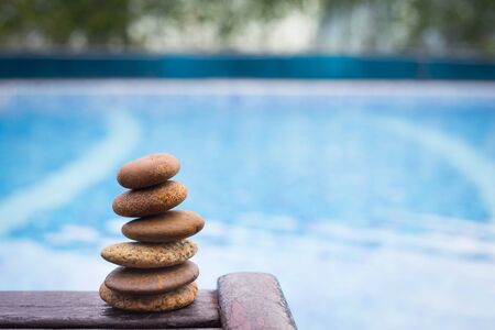 Zen stones on wooden banch on poolの写真素材