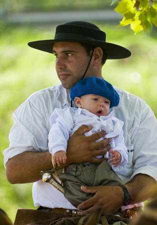 TACUAREMBO ,URUGUAY -  MAR. 7 2009 : Gaucho holding his childのeditorial素材
