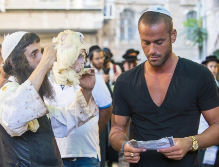 JERUSALEM - SEP 25 : An ultra Orthodox Jewish man waves a chicken over other man during the Kaparot ceremony held in Jerusalem Israel in September 25 2012 のeditorial素材