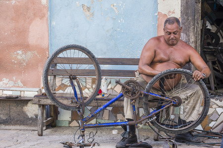 HAVANA, CUBA - JULY 18 : Cuban man fixing bicycle in old Havana street on July 18 2016. The historic center of Havana is UNESCO World Heritage Site since 1982.のeditorial素材