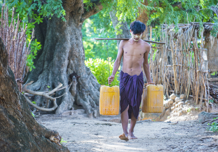 BAGAN, MYANMAR - SEP 06 : Burmese Farmer carrying plastic buckets filled with water in a village near Bagan on September 06 2017のeditorial素材