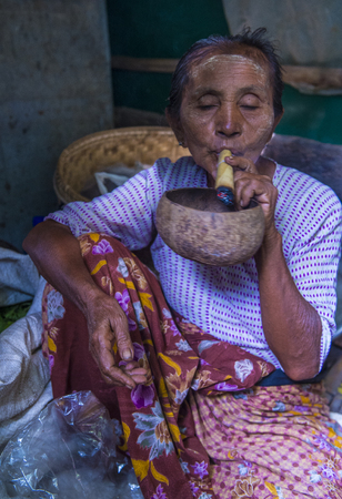 BAGAN, MYANMAR- SEP 04 : Woman smoking a cheroot cigar in market in bagan, Myanmar on September 04, 2017. Cheroot is a cigar made by dried fruits and little bit of tobaccoのeditorial素材