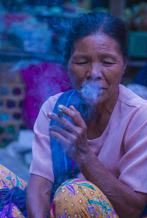BAGAN, MYANMAR- SEP 04 : Woman smoking a cheroot cigar in market in bagan, Myanmar on September 04, 2017. Cheroot is a cigar made by dried fruits and little bit of tobaccoのeditorial素材