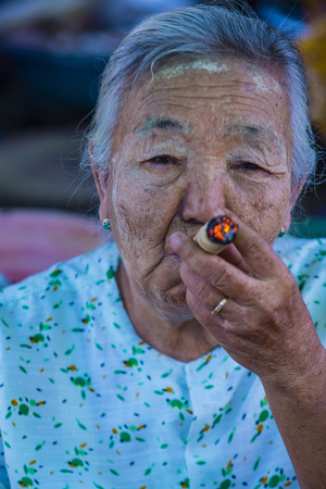 BAGAN, MYANMAR- SEP 04 : Woman smoking a cheroot cigar in market in bagan, Myanmar on September 04, 2017. Cheroot is a cigar made by dried fruits and little bit of tobaccoのeditorial素材