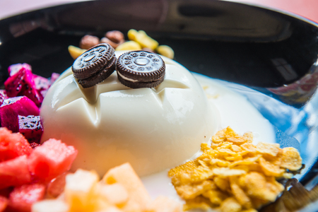 Cold tofu pudding with fruit and dessert on black dish, Thailand.の写真素材