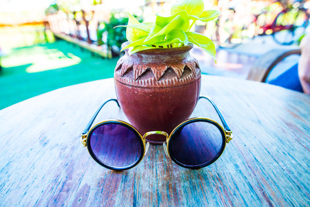 Sunglasses with vase on table, Thailand.の写真素材