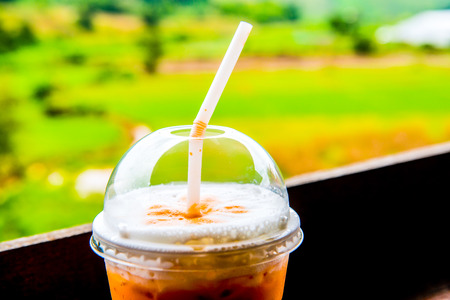 Iced Milk Tea in Plastic Glass with Natural View, Thailand.の写真素材