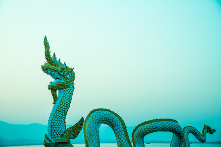 White Naga statue at Kwan Phayao with evening sun, Thailand.
