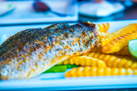 Grilled salted snapper with french fries on white plate, Thailand.の写真素材