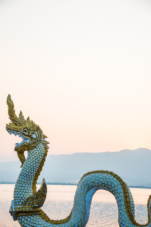 White Naga statue at Kwan Phayao with evening sun, Thailand.の写真素材