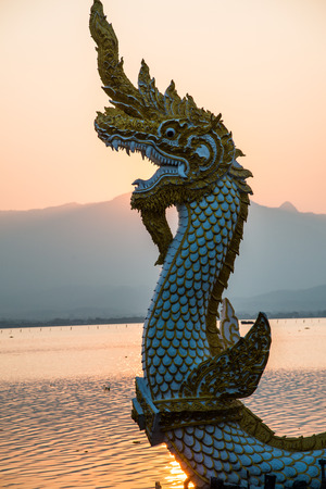 White Naga statue at Kwan Phayao with evening sun, Thailand.の写真素材
