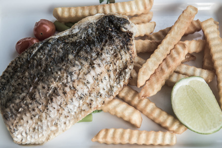 Grilled salted snapper with french fries on white plate, Thailand.の写真素材
