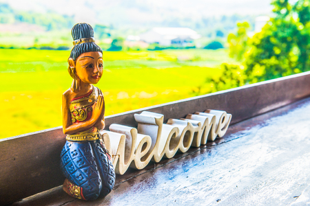 Thai Style Wooden Doll with Welcome Wooden Sign, Thailand.の写真素材
