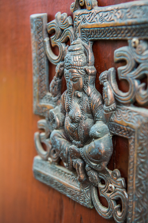 Metal Ganesha on wood panel, Thailand.の写真素材