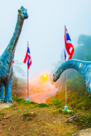 Statue of Chiang Muan dinosaur with curve road, Thailand.の写真素材
