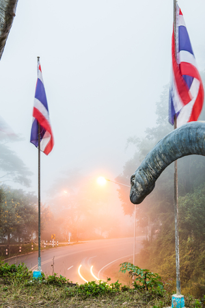 Statue of Chiang Muan dinosaur with curve road, Thailand.の写真素材