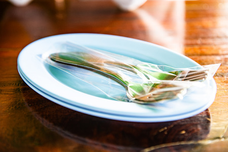 fork and spoon in plastic bag on plate, Thailand.