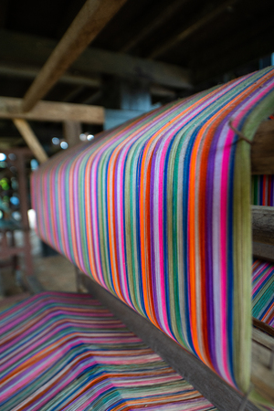 Colourful threads on an ancient wooden loom, Thailand.の写真素材