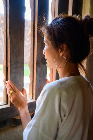 Thai woman in Thai native dress beside the window, Chiang Mai.の写真素材