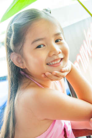 Asian little girl in pink dress is smiling, Thailand.の写真素材
