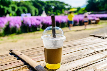 Fresh ice tea in plastic glass with flower garden, Chiang Mai province.