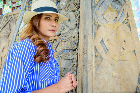 Thai Girl in Blue Dress with Ancient Wood Carving Background, Nan Province.の写真素材