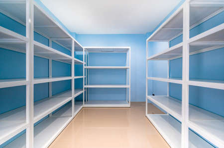 Empty white shelves in blue storage room, Thailand.の写真素材