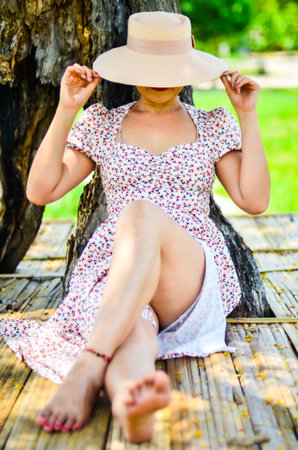 A girl in a hat sitting in the garden, Thailand.の写真素材