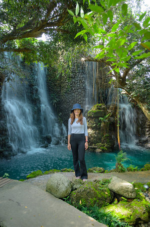 Asian tourist woman with waterfall background in shady garden, Chiang Mai Province.の写真素材
