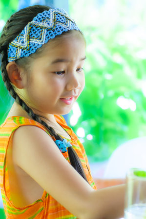 A cute little Asian girl in an orange dress is showing emotions and gestures.の写真素材