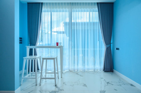 Home Decoration Series : White bar table in a light blue room and large sliding glass doors with light shining through. A coffee table and chair set for the living room in cool colors. The interior decoration is airy and comfortable.の写真素材
