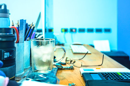Office Series : Cold water in a double walled Insulated drinking glasses on a computer desk for working. Cool light colored office room. A workspace that generates ideas.の写真素材