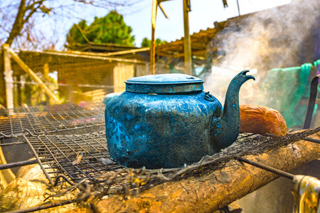 Object Series : Old kettle on charcoal stove. A worn aluminum kettle sits on a metal grate. A kettle that has been used for a long time in the countryside.の写真素材
