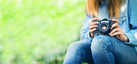 girl in blue jeans sitting with vintage camera