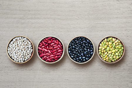 varieties of beans in plates on wooden background