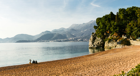 Young family on a deserted beach and mountains background landscape. Sveti Stefan, Montenegro.の写真素材