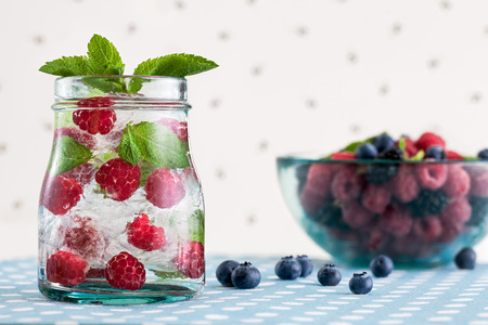 Fresh raspberry mojito and a glass bowl with berries on a white polka-dotted backgroundの写真素材