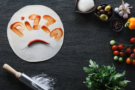 Italian pizza cooking process. Pizza dough with a ketchup inscription.の写真素材