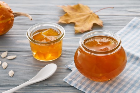 Fresh pumpkin jam with autumn leaves and little decorative pumpkin on a blue wooden tableの写真素材