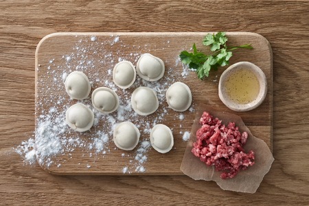 Raw Meat dumplings Russian traditional pelmeni and the ingredients: minced meat, oil and herbs.の写真素材
