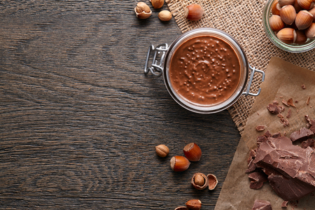 Glass jar with hazelnut spread and ingredients on dark wooden backgroundの写真素材