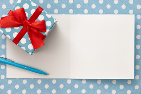 Greeting card with space for texting, polka dot gift box and a blue pen on a dotted background. All in focus.の写真素材
