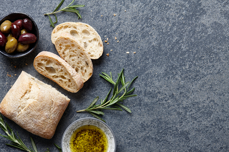 Italian food background with ciabatta bread, olive oil, olives and rosemaryの写真素材